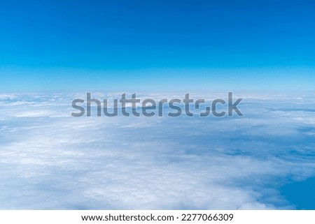 A view of the blue sky and fluffy clouds, a picture taken from the window of an airplane.
