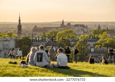 Unidentified people engoying sunset on the Krakus Mound with an amazing view of the historical part of Krakow old town, Poland. It is a popular place to watch sunset in Cracow. Royalty-Free Stock Photo #2277076733