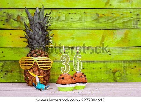 Creative card postcard happy birthday with number  36. Background character pineapple in festive glasses. Copy space anniversary card on yellow colorful wooden background.