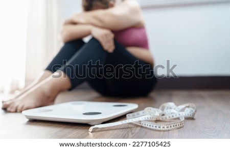 Obese Woman with fat upset bored of dieting Weight loss fail  Fat diet and scale sad asian woman on weight scale at home weight control. Royalty-Free Stock Photo #2277105425