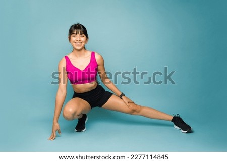 Happy fit young woman smiling while stretching her legs looking flexible ready to start exercising