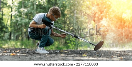 a boy with a metal detector in the park is looking for a treasure. High quality photo