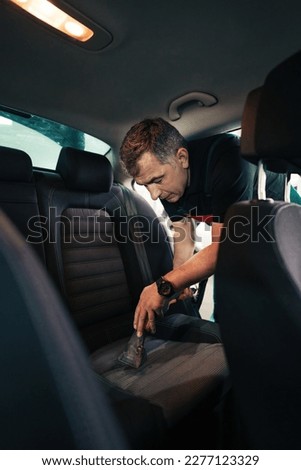 Professional worker cleaning car interior and backseat, car detailing (or valeting) concept. Selective focus. Ultra wide angle shot. Royalty-Free Stock Photo #2277123329