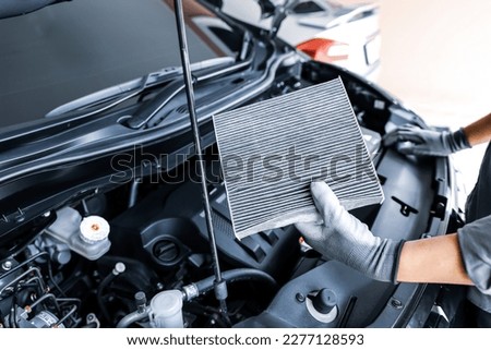 Auto mechanic checking, cleaning and replacing car air filter. Concept of car care service maintenance. Royalty-Free Stock Photo #2277128593