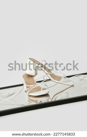 Creative studio shot of white strappy lace up block heel sandals, product photography