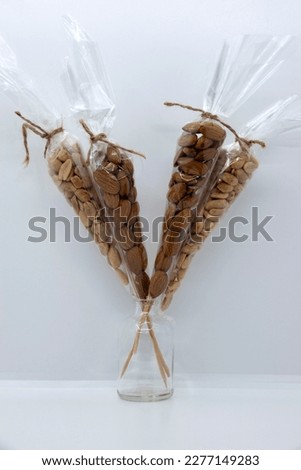 Almonds and peanuts in a transparent package on a gray-white background.