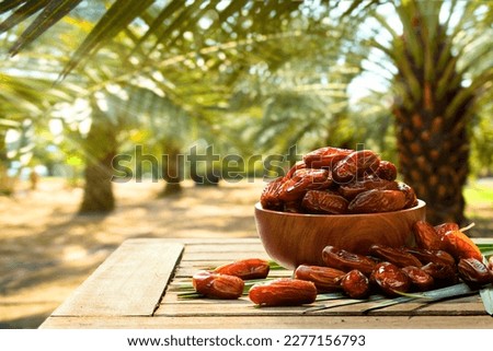 Dried dates fruits with dates palm plantation background. Royalty-Free Stock Photo #2277156793