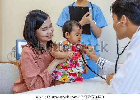 Mother holding cute baby in doctor's office Asian male pediatrician prescribes patient treatment. Medical. Pediatric doctor. Pediatrics. Family Medicine and Clinic Health care and prevention concept.