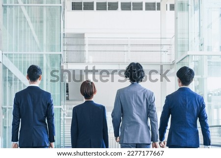Businessmen and women walking down an office corridor Royalty-Free Stock Photo #2277177667