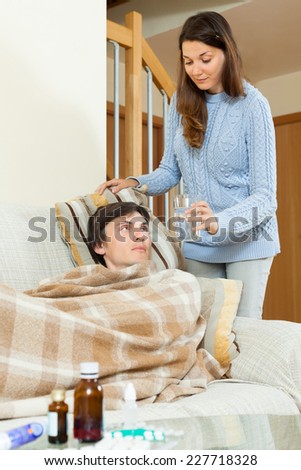 Woman giving medicinal tablet to  husband at home