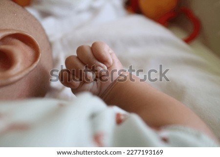 a photo of one hand of a newborn in a grasping position with the thumb inside