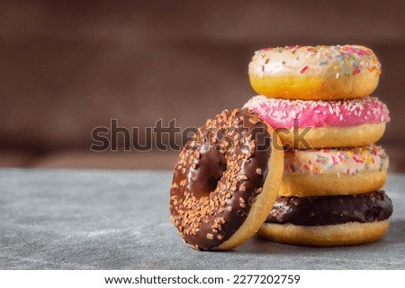 Set of multicolored sweet donuts donuts with icing and sprinkles on a brown background with copy space