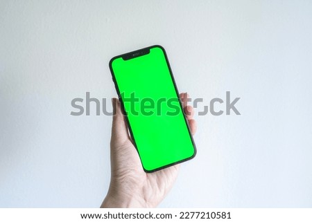 Hand holding a smartphone with green screen template for social media, web or app mock up