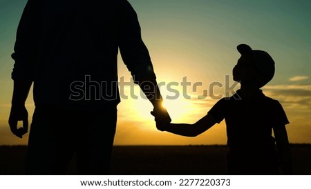 Little son, dad hold hands close up in nature in sun. Child father walk in park at sunset, family trust concept. Parent, kid boy outing together. Adoption of child. Happy family, teamwork. Silhouette