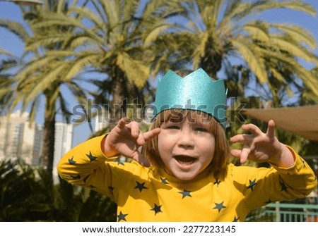 A small boy in a crown on a background of palm trees. Concept: birthday, little prince, royal vacation, family trip