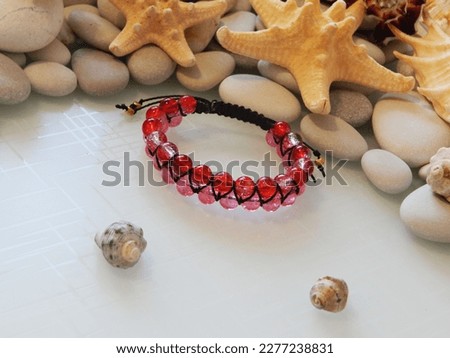 Hippie red bracelet on a white. Red friendship bracelet and pebble