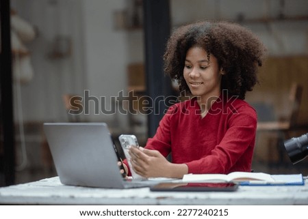 Young African American businesswoman working on smart phone and laptop computer with pile of documents workplace, business finance and accounting concepts. Royalty-Free Stock Photo #2277240215