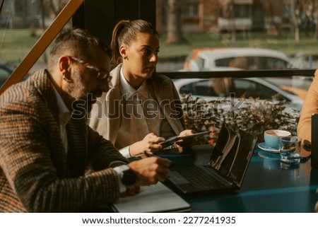 Middle-aged businessman and young businesswoman working remotely at the coffee bar