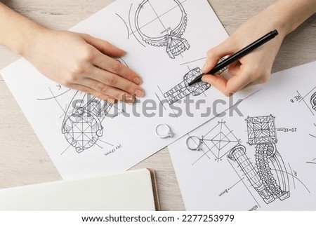 Jeweler drawing sketch of elegant ring on paper at wooden table, top view Royalty-Free Stock Photo #2277253979