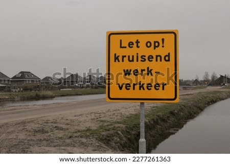 Road work sign with Dutch text saying 'Let op! Kruisend werkverkeer: Translation: Attention!  Truck crossing