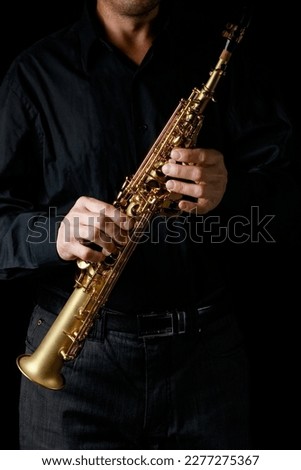 soprano saxophone in hands on a black background Royalty-Free Stock Photo #2277275367