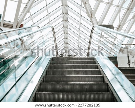 Escalator to the upper floor against the window. the stacked ceiling in the mall.