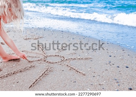 Happy child draw pictures in the sand of the sea in the summer on the nature