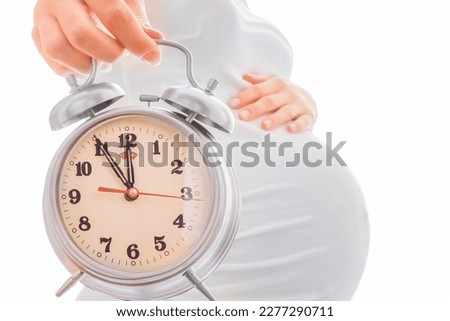 beautiful young pregnant girl on a white background with alarm clock