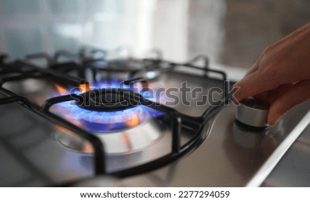 Woman turning on the gas burner on the stove. Royalty-Free Stock Photo #2277294059