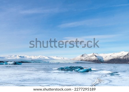 Panoramic view over the frozen glacial lagoon with the terminus or end of the Jokulsarlon glacier, Iceland with in forefront various blue arctic icebergs and snow covered mountain range in background Royalty-Free Stock Photo #2277295189