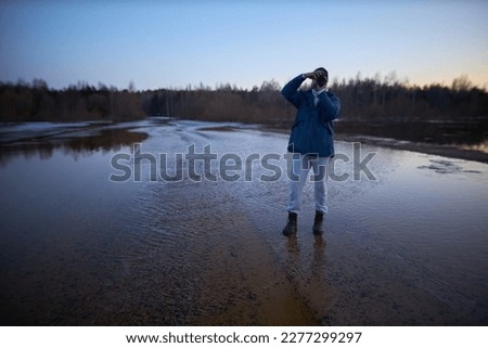 Photographer standing in the water and taking pictures.