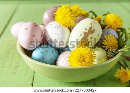 Happy Easter Holidays. Handmade Easter colorful eggs and spring flowers dandelions on a rustic wooden table. Easter composition.