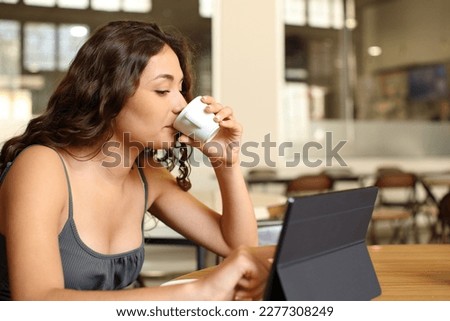 Woman drinking coffee and using tablet in a restaurant
