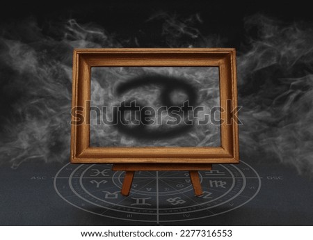Abstract image of the sign of the zodiac Cancer against the background of smoke in a frame on a stand