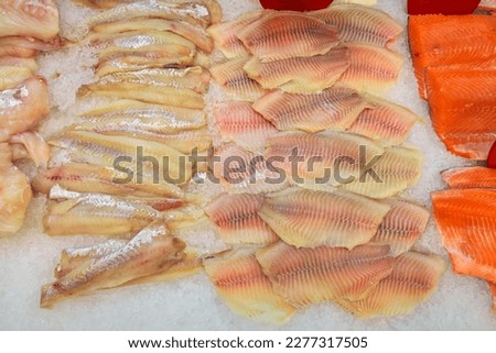 Frozen fish fillets on ice for sale in supermarket. Fresh raw sea food top view