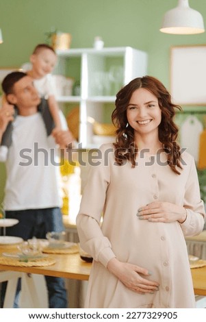 pregnant mom against the background of son and dad In the kitchen. the concept of family happiness. a cozy house and a mortgage for buying a house and an apartment, a loan for furniture and repairs.
