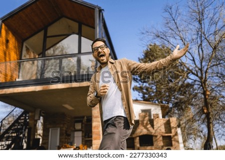 One man caucasian adult male stand outdoor in front of modern tiny house host or salesman with hands gesture invite in gesturing invitation happy smile in sunny day copy space