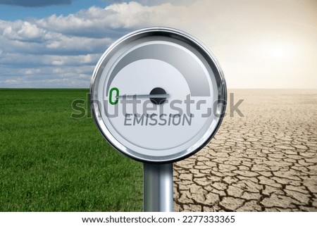 Gauge with inscription EMISSION and arrow points to zero on a background of landscape with half green field and half desert. Royalty-Free Stock Photo #2277333365