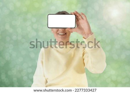 A woman is holding a phone with a blank display. Abstract background.