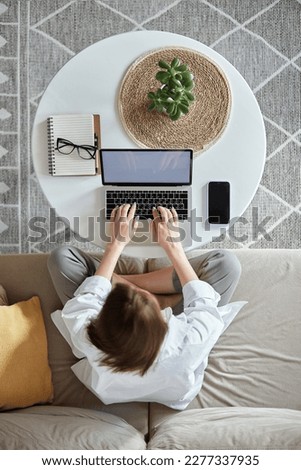 Mockup white screen laptop woman using computer sitting on sofa at home, top view Royalty-Free Stock Photo #2277337935