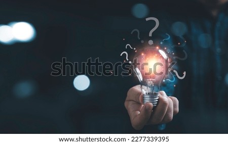 Businessman holding glowing lightbulb and question mark with copy space for creative thinking idea and problem solving concept. Royalty-Free Stock Photo #2277339395