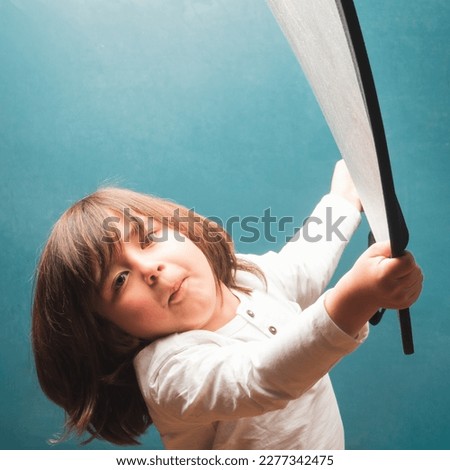 Child playing with the reflector during the photo session in front of the blackboard in a school classroom.