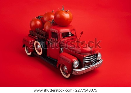 red truck delivers fresh tomatoes. Vintage red toy truck on a red background.