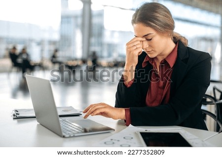 Overworked exhausted frustrated caucasian woman, company employee, administrator or secretary, sits at her work desk, massages the bridge of her nose, feels tired from work, stress, headache Royalty-Free Stock Photo #2277352809