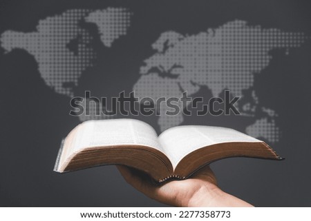 Hand holding Holy Bible and world map in blur background. World mission christian idea. Copy space for text. Christian background for great commission or earth day concept.
