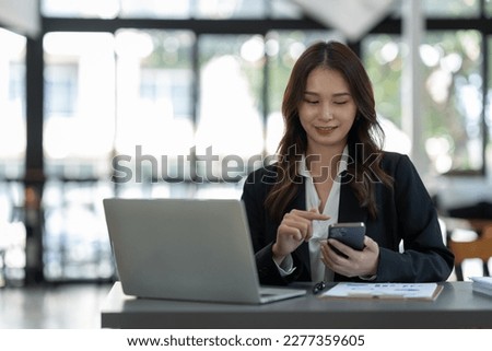 Attractive Asian businesswoman using a mobile phone at the office for making contact Talk about online business. and financial income happily.

