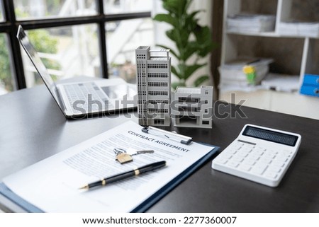 Pictures of pens, calculators, building models, condos, laptops, keys, and detailed trading documents used to calculate interest, taxes, and profits for investment in real estate.