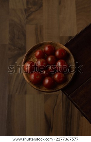Solanum lycopersicum var. cerasiforme - Cherry tomatoes on plate and wood background