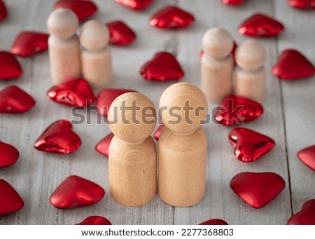 Little red hearts and wood figures pieces simulate a couple on white wood background. Couple love and harmony concept.