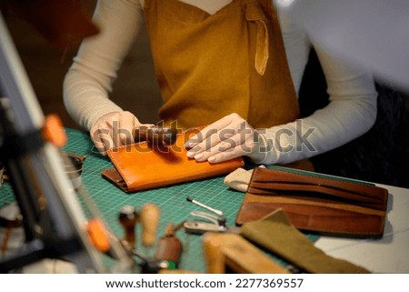 young talented woman polishing edges od wallet with slicker, burnisher creating sewing leather handmade wallet leathercraft, close up cropped shot. free time, spare time, lifestyle Royalty-Free Stock Photo #2277369557